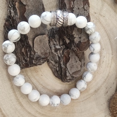 Pulseira de contas brancas com veios cinzentos e contas metálicas prateadas numa base de madeira