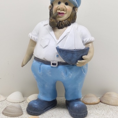 Estátua de marinheiro com barco e conchas sobre areia