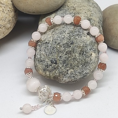 Pulseira com contas rosa e castanho sobre pedras naturais cinza e bege