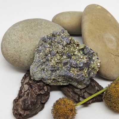 Pedra mineral com cristais dourados e púrpuras junto a pedras e elementos naturais