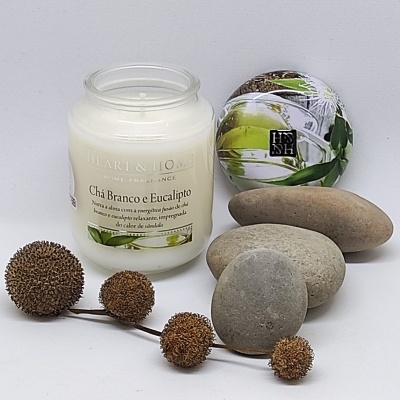 Vela perfumada em jarra de vidro com tampa decorativa, pedras cinzentas e elementos decorativos secos