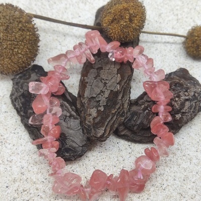 Pulseira de pedras naturais rosa sobre casca e flores secas