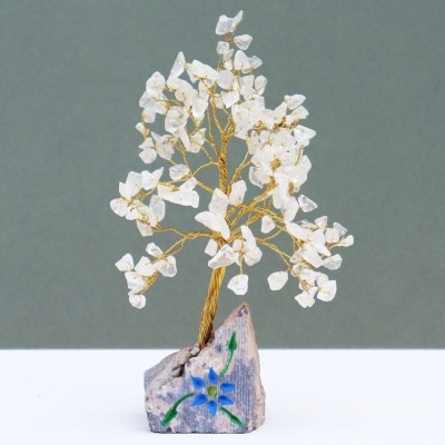 Árvore decorativa de fios dourados com pedras brancas numa base de pedra pintada com flor azul.