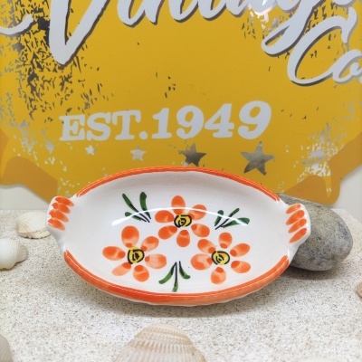 prato oval decorativo com flores laranja sobre mesa com conchas e fundo amarelo