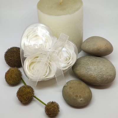 Conjunto decorativo com vela branca, pedras cinza, flores artificiais brancas e flores secas castanhas