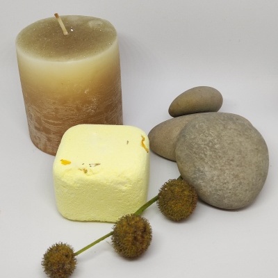 Vela bege, cubo amarelo, três pedras cinzentas e ramo com bolas secas marrons