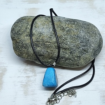 Colar com pendente azul de pedra polida sobre pedra cinzenta