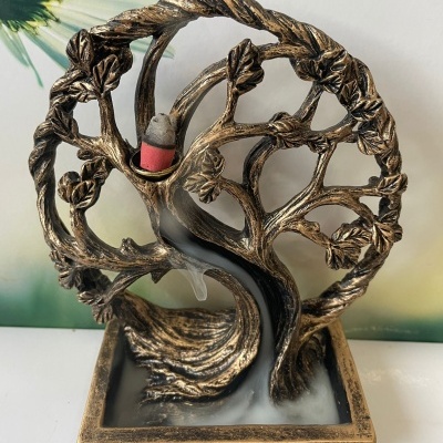 Incensário em formato de árvore dourada com cone de incenso vermelho e fumo descendo