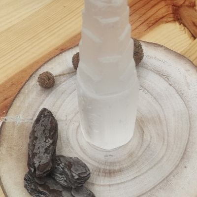 Torre de cristal branco translúcido sobre base de madeira clara e cascas escuras