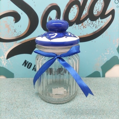 Frasco de vidro com tampa cerâmica e fita azul diante de fundo com texto