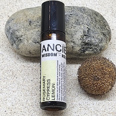 Frasco pequeno de roll-on com etiqueta branca e amarela ao lado de pedra e semente sobre superfície clara