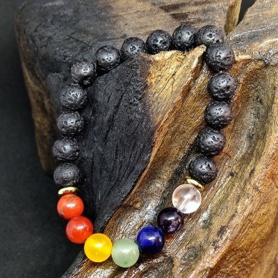 Pulseira de pedras coloridas e vulcânicas sobre madeira escura