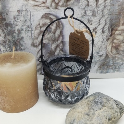 Vela castanha, lanterna de vidro cinzento com suporte preto, pedra cinzenta em mesa branca