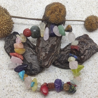 Pulseira de pedras semi-preciosas coloridas sobre pedaços de casca e flores secas