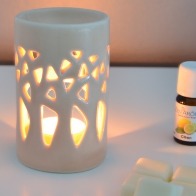 Difusor de cerâmica branco com vela acesa e óleo essencial Citron em frasco pequeno