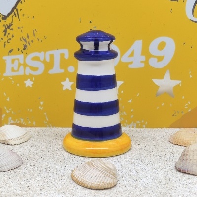 Farol decorativo azul e branco com base amarela e conchas sobre superfície granulada