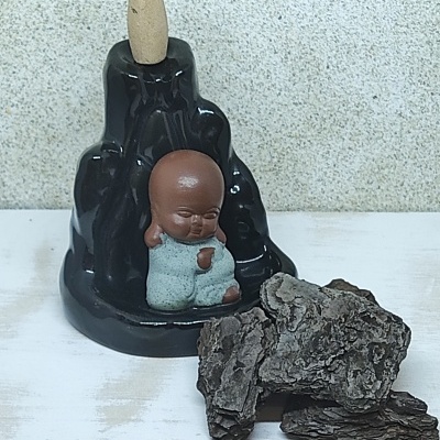 Incensário preto com estátua de bebé e cone de incenso ao lado de casca de árvore