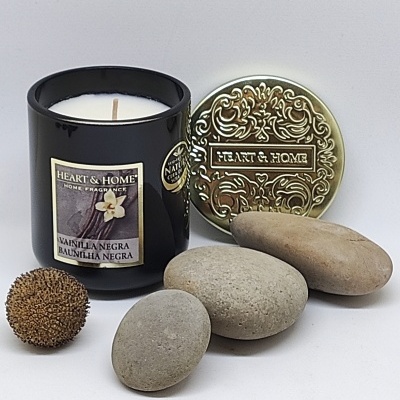 Vela perfumada com rótulo e tampa decorativa dourada, pedras naturais e semente marrom sobre fundo branco