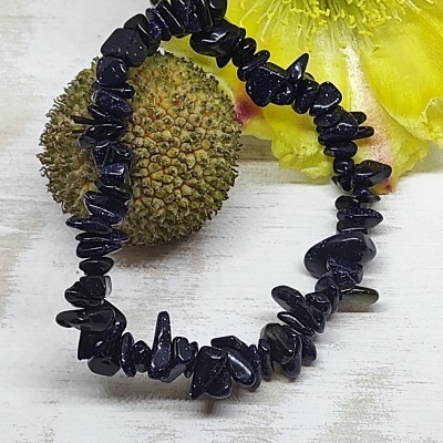 Pulseira de pedras pretas elástica com flor amarela e semente ao lado