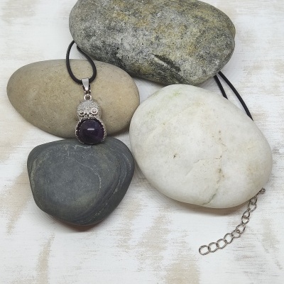 Colar com pendente de coruja em prata e pedra roxa sobre pedras lisas coloridas