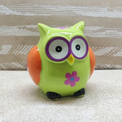 Figura decorativa de coruja verde com asas laranja e olhos grandes