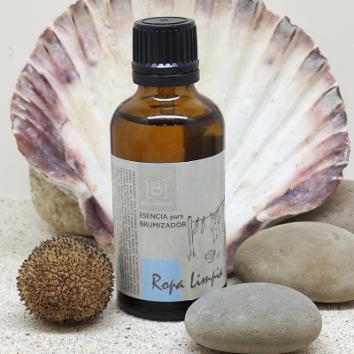 Frasco âmbar com essência para brumizador com etiqueta, concha e pedras sobre areia