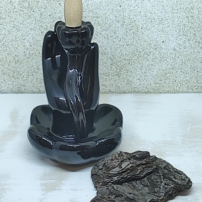 Suporte de incenso preto com cone bege e pedaços de casca seca