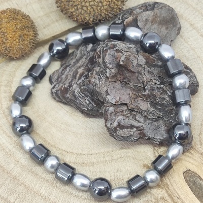 Pulseira metálica em diferentes formatos sobre casca de árvore e fundo de madeira