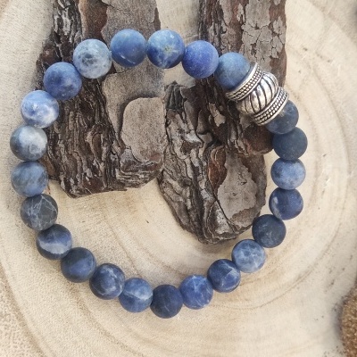 Pulseira de contas azuis com espaçador metálico sobre madeira clara