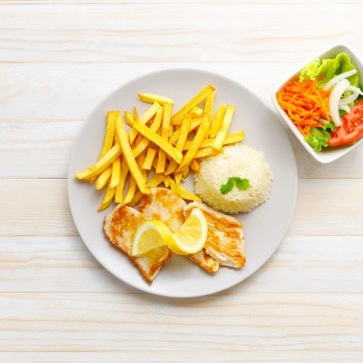 Prato com peixe grelhado, limão, arroz, batatas fritas e salada colorida