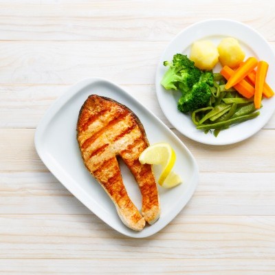 posta de salmão grelhado com legumes cozidos e fatia de limão em pratos brancos