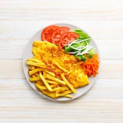 Prato com omelete, batatas fritas e salada fresca