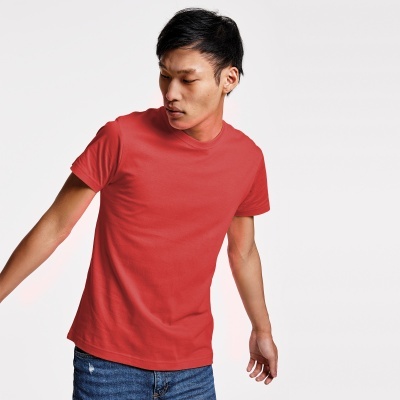 Homem a usar t-shirt vermelha e calças de ganga, fundo branco