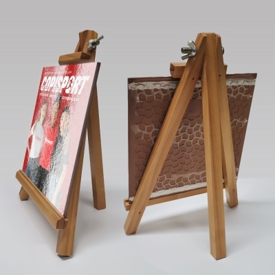 Dois cavaletes de madeira, um com revista CORSPORT, o outro com tecido castanho texturizado