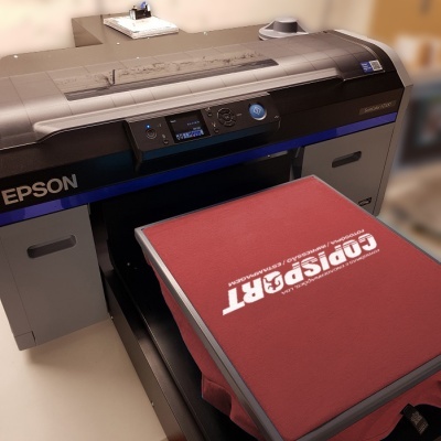Impressora Epson a imprimir t-shirt vermelha com texto branco