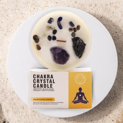 Vela Chakra Crystal com cristais e embalagem amarela branca sobre superfície clara