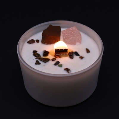 Vela aromática branca em vidro fosco com pedras decorativas e cristais, acesa