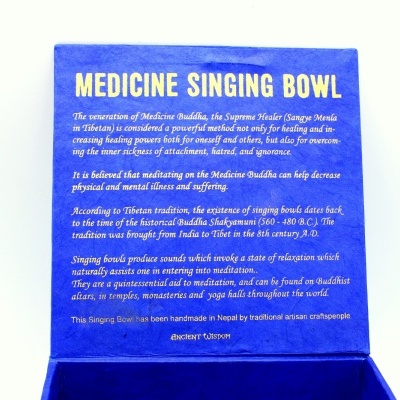 Caixa azul com texto em inglês detalhando informações sobre o taça de canto de medicina budista