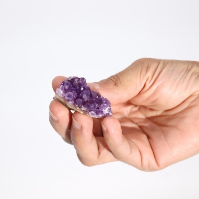 Mão segurando pedra cristalizada roxa