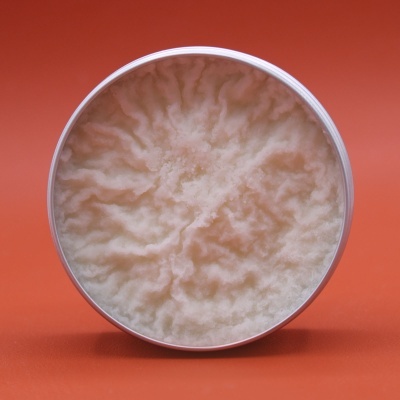 Pote branco aberto com creme de textura ondulada cor creme sobre fundo laranja
