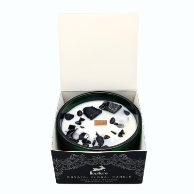 Vela decorativa com cristais pretos em recipiente preto, dentro de embalagem preta com texto.