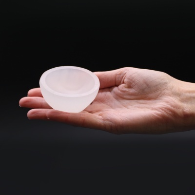 Bol de silicone branco translúcido em mão sobre fundo preto