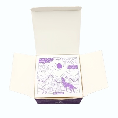 Embalagem com ilustração de lobos, montanhas e lua em roxo.