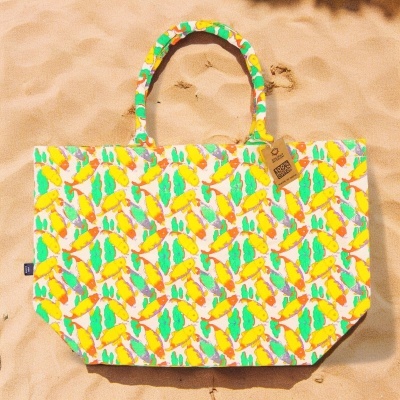 Saco de praia colorido com padrão de folhas em fundo de areia