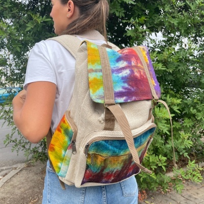Mochila bege com detalhes tie-dye coloridos usada por pessoa ao ar livre
