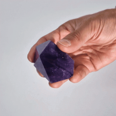 Cristal de ametista roxa polida em forma hexagonal na mão
