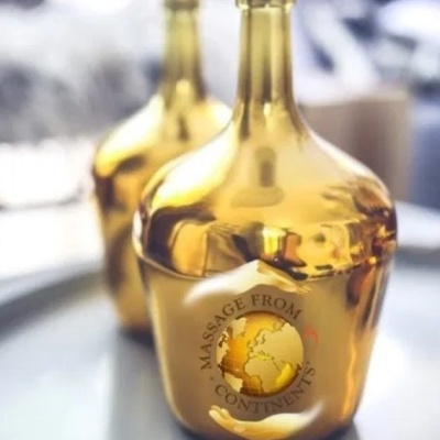 Duas garrafas douradas com texto 'MASSAGE FROM 5 CONTINENTS'