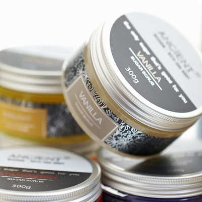 Frascos de esfoliante de açúcar com etiquetas de diferentes sabores em tons neutros e tampas metálicas