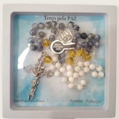 Terço com contas coloridas e crucifixo numa embalagem com texto em português.