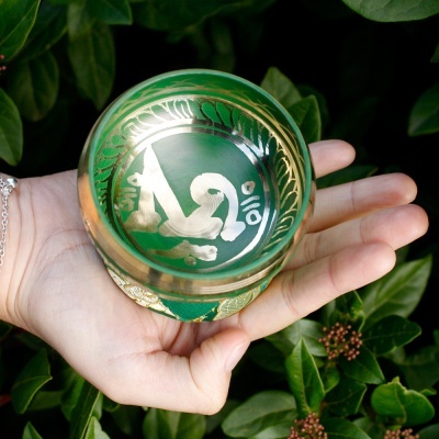 Bola decorativa verde e dourada com escrita árabe nas mãos